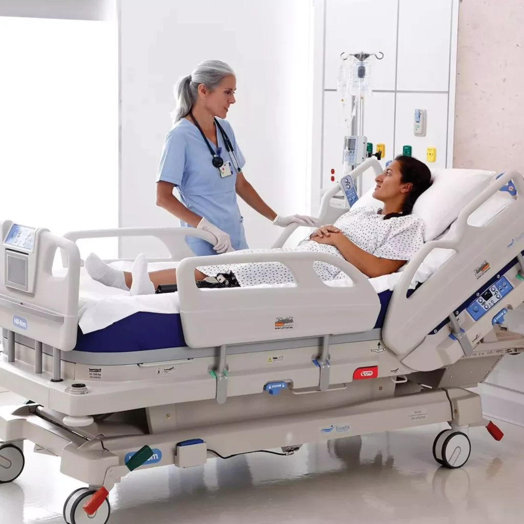 A nurse providing ICU care at home in Ranchi talks to a patient in a hospital bed