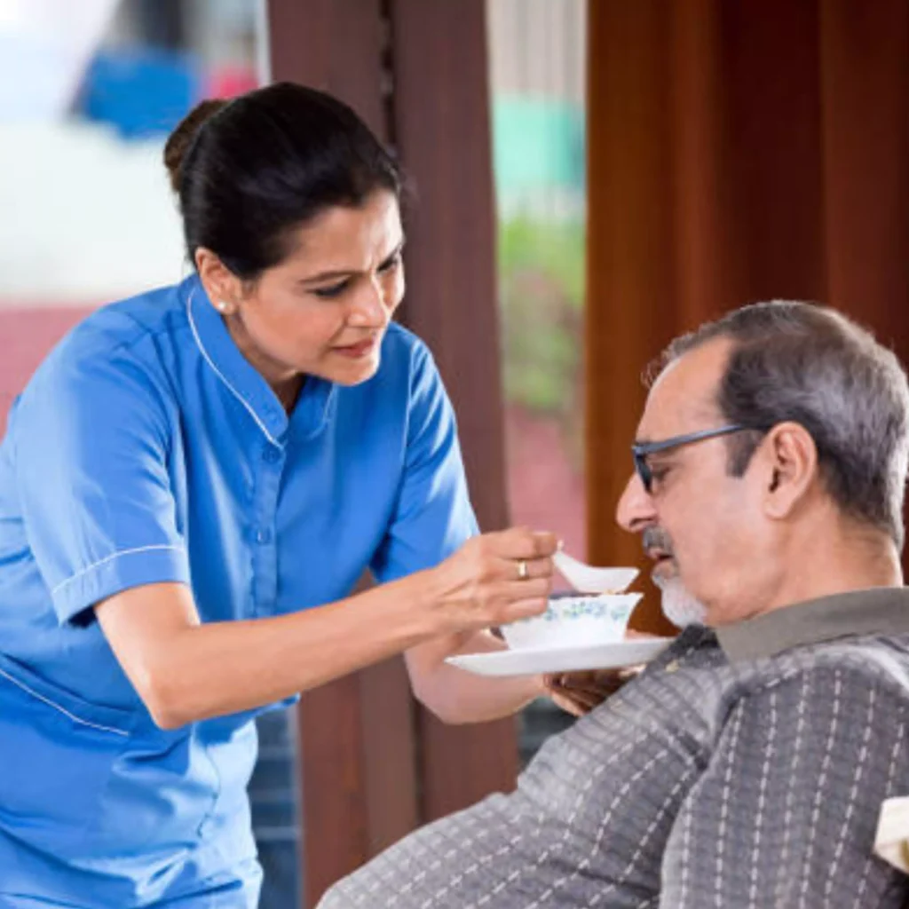 A nurse in Ranchi providing nursing care services, serving a man a cup of tea. 24/7 home nursing services in ranchi