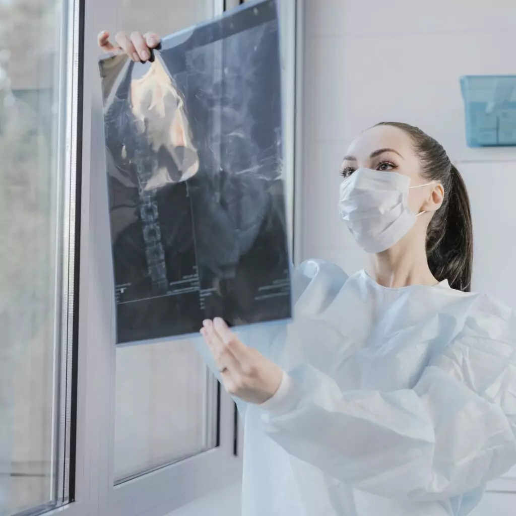 Woman wearing a surgical mask displays an X-ray in a home setting in Ranchi. x ray at home, nursing care service, home nursing services