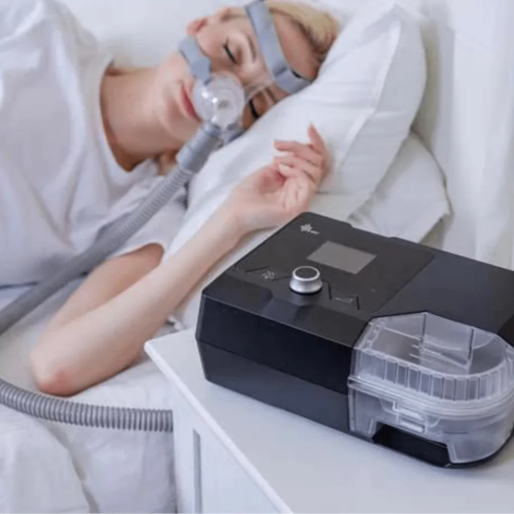 Image of a woman resting in bed with a CPAP machine.